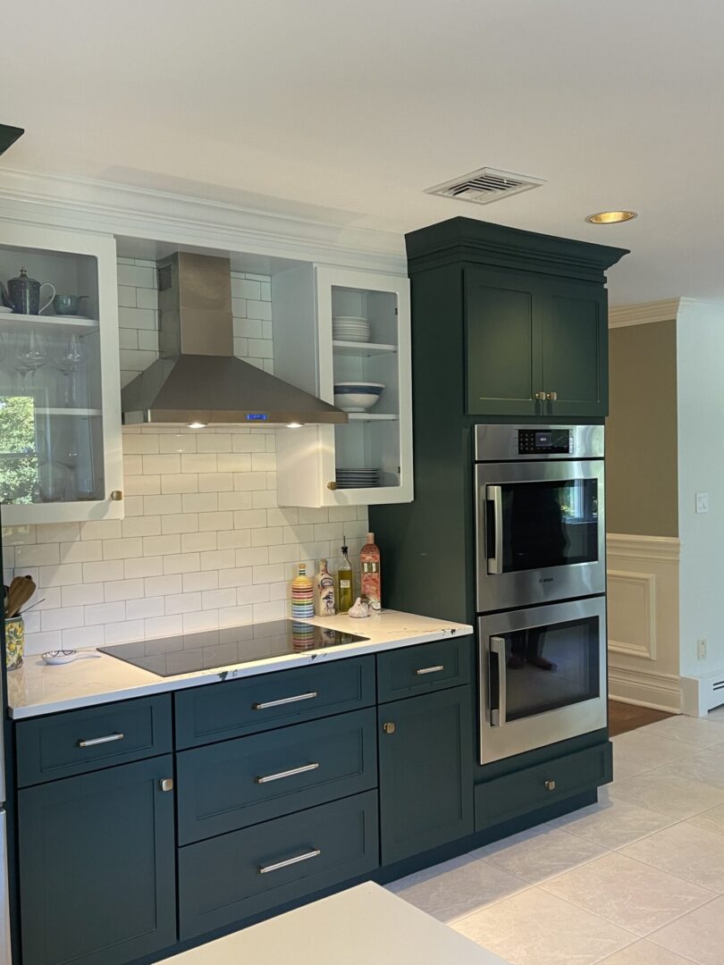 A kitchen with green cabinets and white walls.