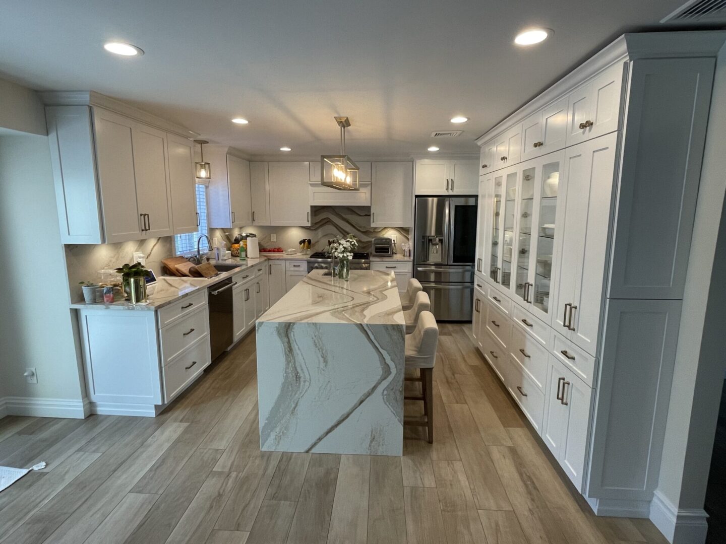 A kitchen with white cabinets and marble counter tops.