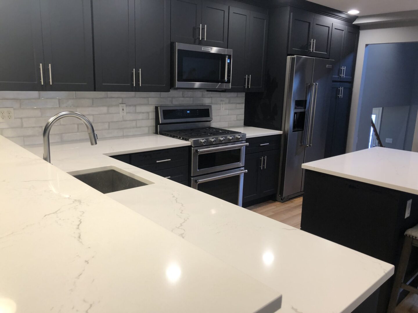 A kitchen with black cabinets and white counters