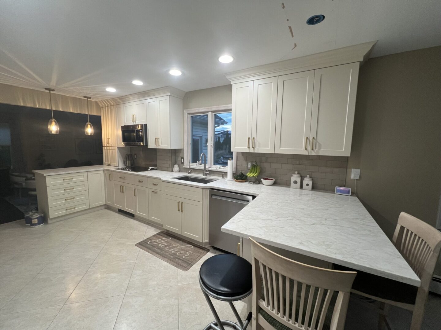 A kitchen with white cabinets and a large window.