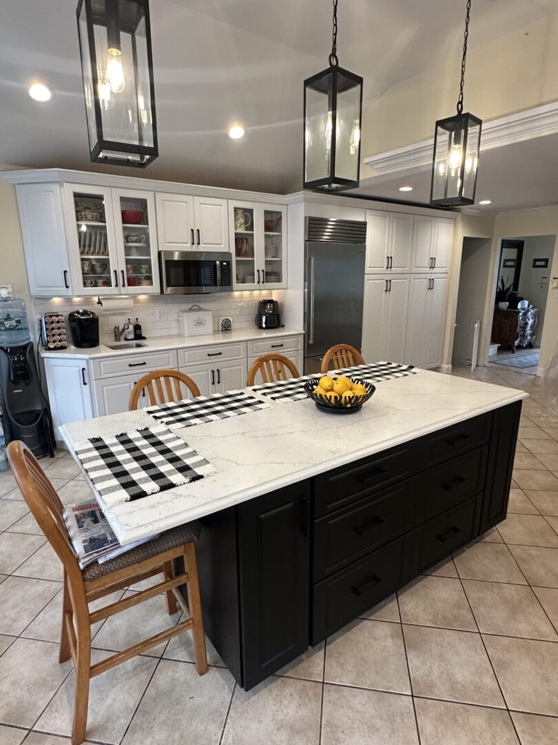 A kitchen with white cabinets and black island.