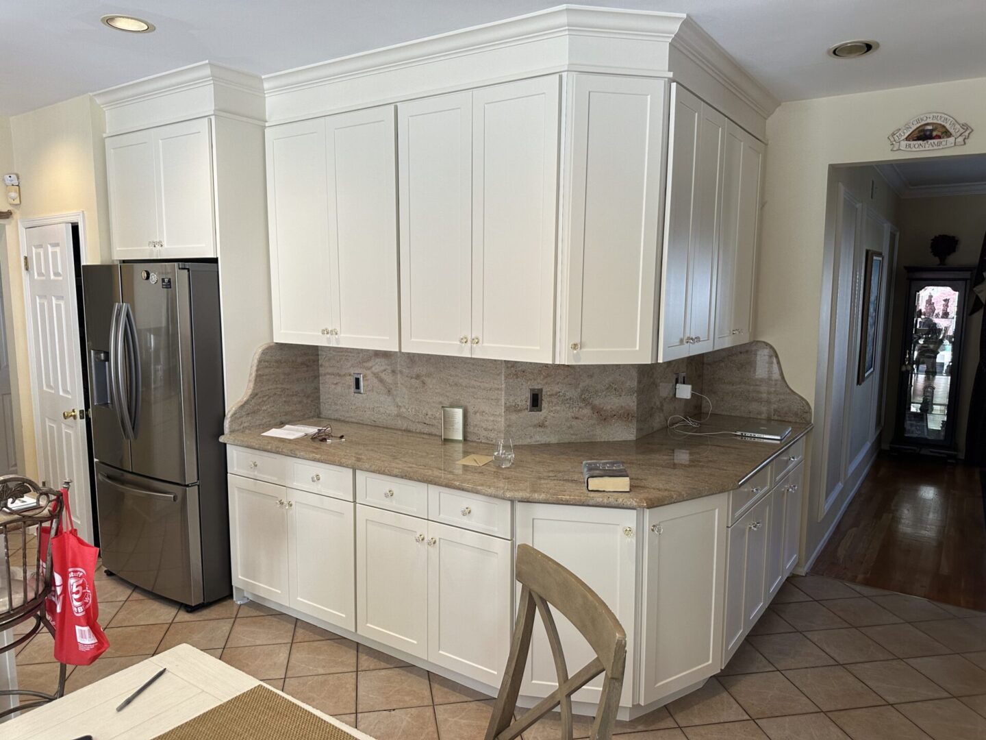 A kitchen with white cabinets and tile floors.