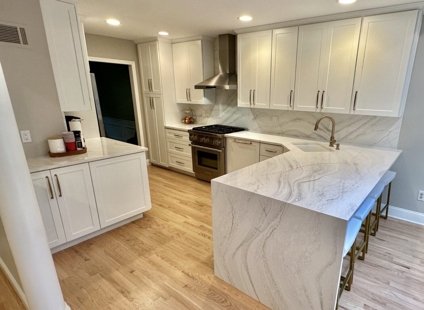 A kitchen with white cabinets and wood floors.