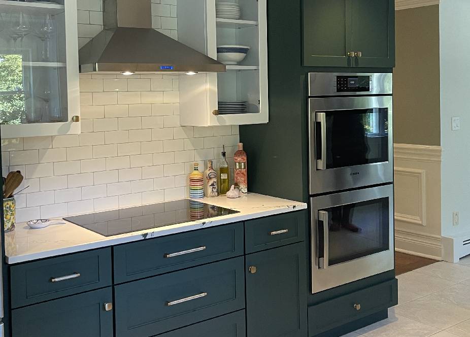 A kitchen with dark green cabinets and white walls.