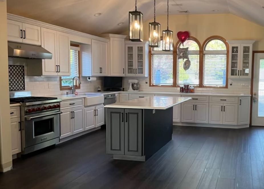 A kitchen with white cabinets and black island.